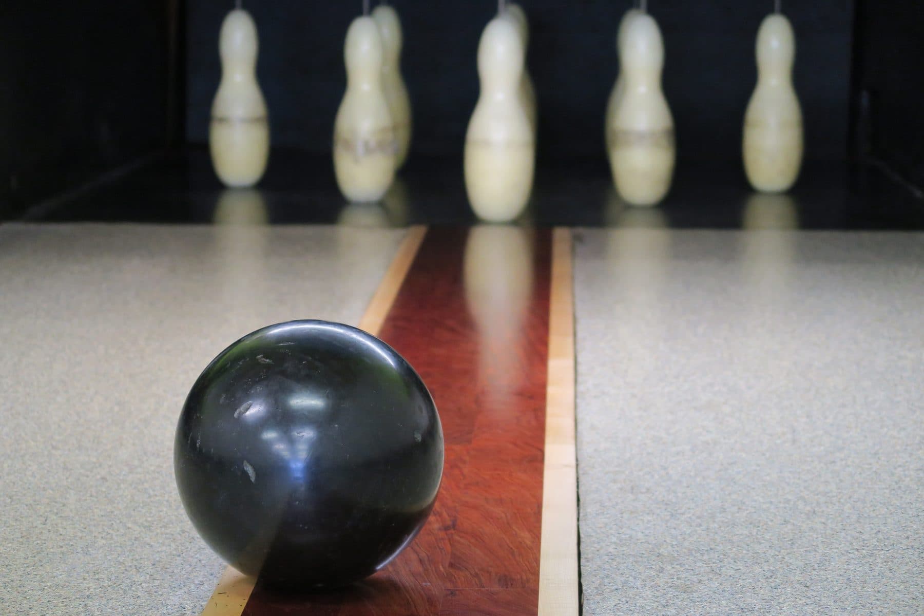Boule en bois sur la planche, face aux neuf quilles